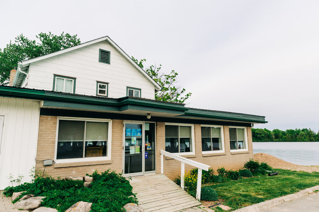 A view of Elim Lodge's Lakeside Dining Room with a sandy beach on Pigeon Lake in the background