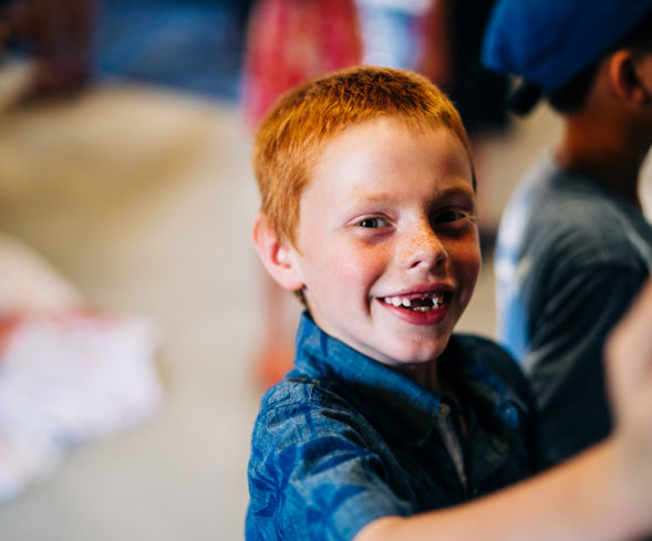 A young boy smiles at a photographer
